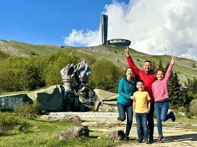 Family posing in front of a monument structure on a hill
