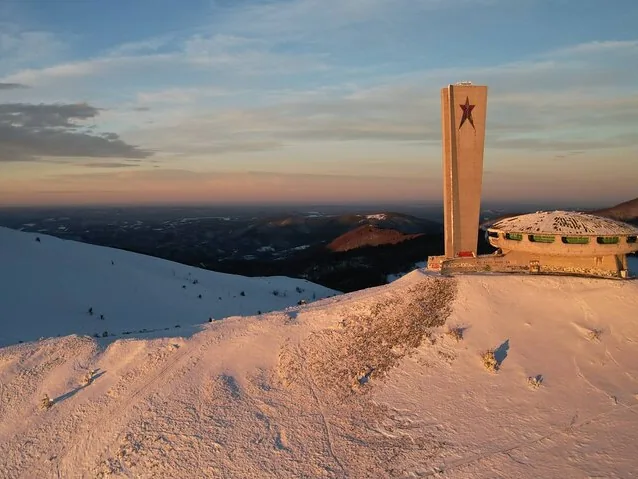 Luftaufnahme des Buzludscha-Denkmals auf einem schneebedeckten Berg bei Sonnenuntergang.