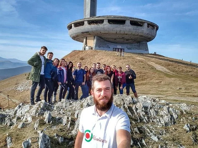Group of people taking a selfie in front of the Buzludzha Monument.