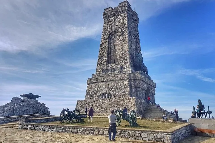 Großes Steindenkmal auf einem Hügel mit Kanonen und Menschen drumherum.